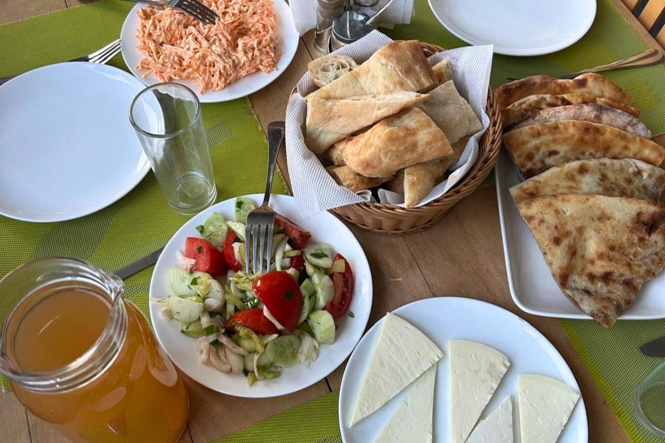 A table featuring plates of traditional Georgian food, including a fresh salad, cheese and filled pastries